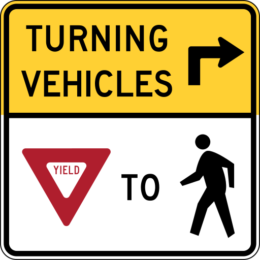 A sign with a yellow top panel that shows the black words TURNING VEHICLES and a black arrow that turns right, and a white lower panel with a red yield triangle, the word TO and a black walking person.
